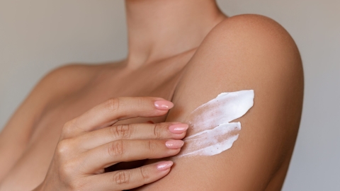 Cropped shot of a young tanned woman moisturizing her shoulder with her hand using a cream